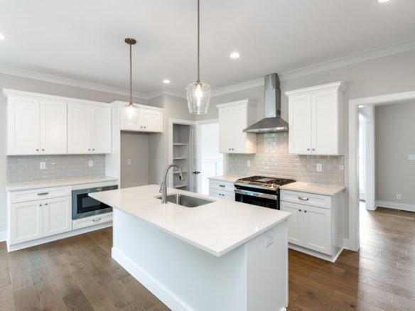 Kitchen with white cabinets, island, and stainless steel stove.
