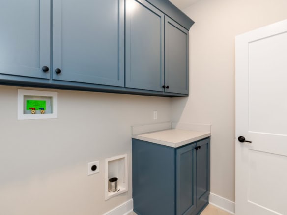 Laundry room with blue cabinets, white countertop, and wall-mounted control panel.