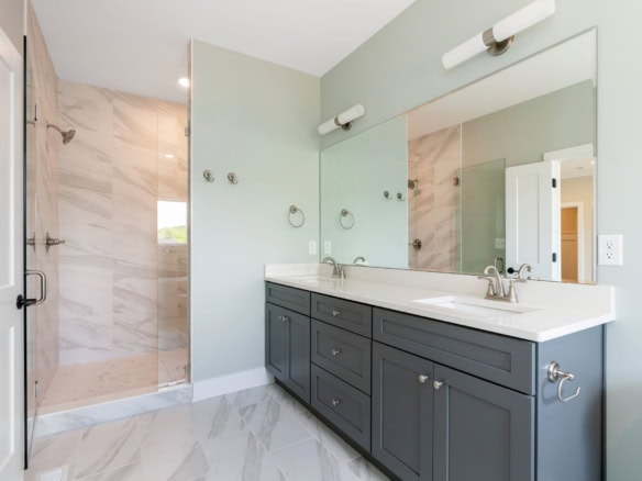 Contemporary bathroom featuring a double vanity, large mirror, and walk-in shower.