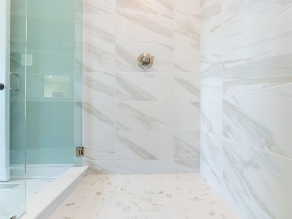 Elegant marble-tiled shower with glass door in a luxury bathroom.