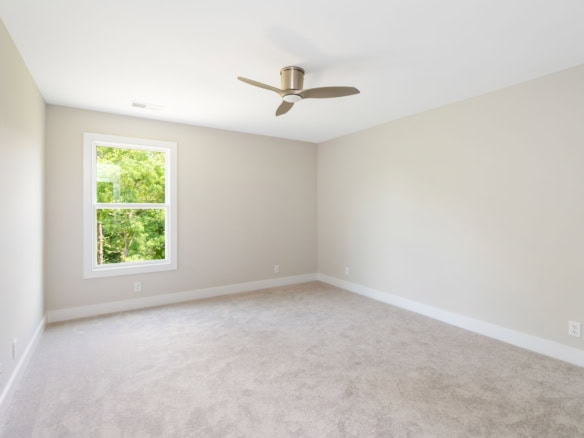 Bright, empty bedroom with a window, ceiling fan, and neutral walls.