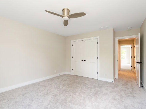 Bright, spacious bedroom with neutral walls and ceiling fan.