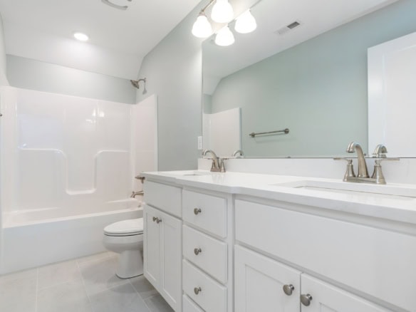 Bathroom featuring a white vanity, dual sinks, and a shower/tub combo.