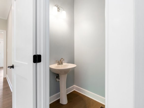Small bathroom with pedestal sink and soft blue wall paint.