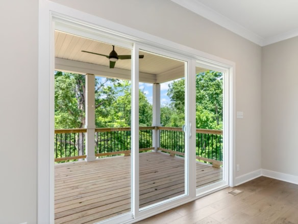 View of a new wooden deck with screened porch overlooking lush greenery.