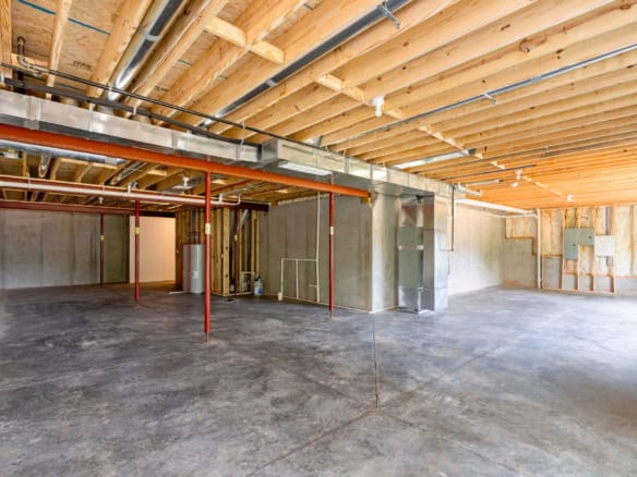 Interior view of a new construction building with exposed wood ceiling and concrete floor.