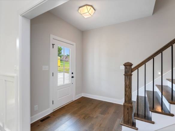 Bright entryway with white walls, wooden flooring, and staircase at 6603 Oakmont Cir.