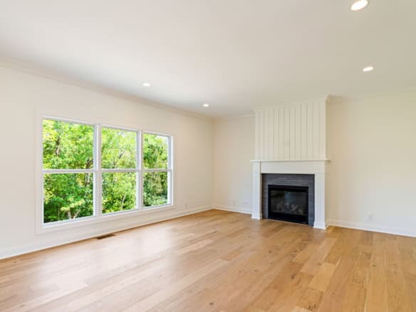 Bright living room featuring a fireplace, large windows, and hardwood floors.
