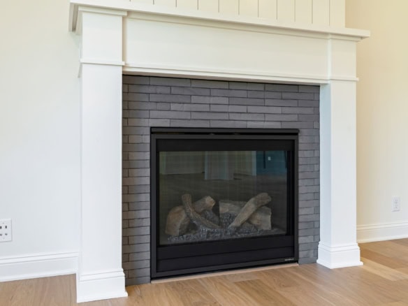 Fireplace with black frame and gray brick surround in living room for home warmth.