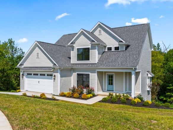 Beautiful white two-story house with a garage, landscaped yard, and blue sky.