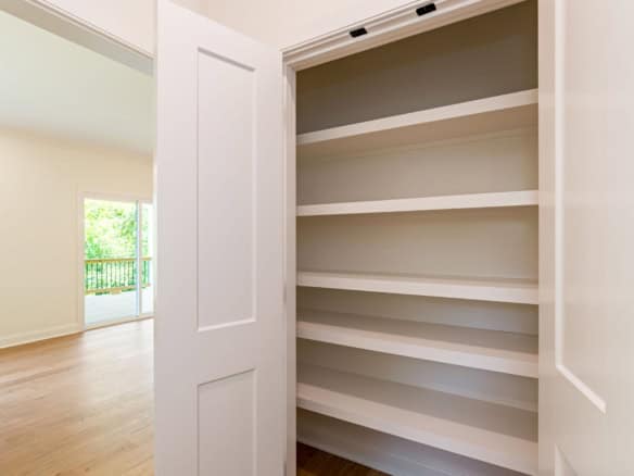 Interior view of a room with built-in white shelves and a sliding door, bright and spacious.