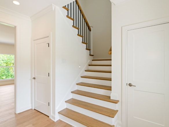 Bright interior staircase with wooden steps and white walls at 6712 Hypoint Ridge Rd.