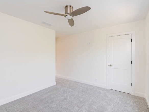 Interior of a bright, clean room with white walls, window, and ceiling fan.