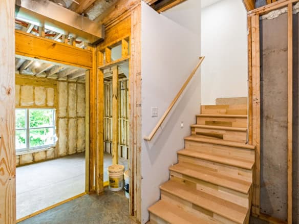 Interior view of a new home under construction showing framing, stairs, and unfinished walls.