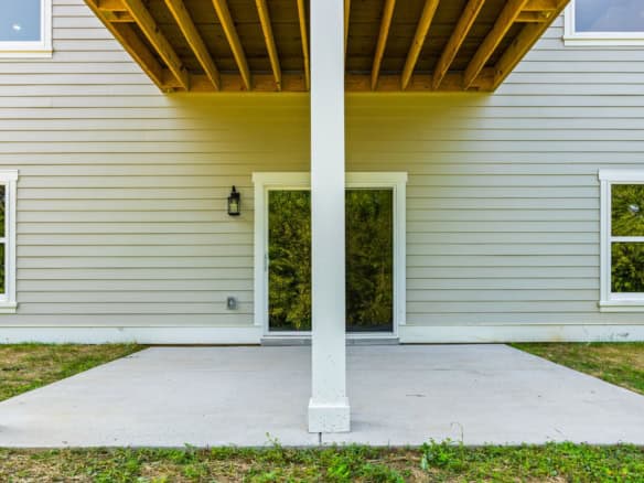 View of a modern house patio with covered area, sliding door, and exterior siding.