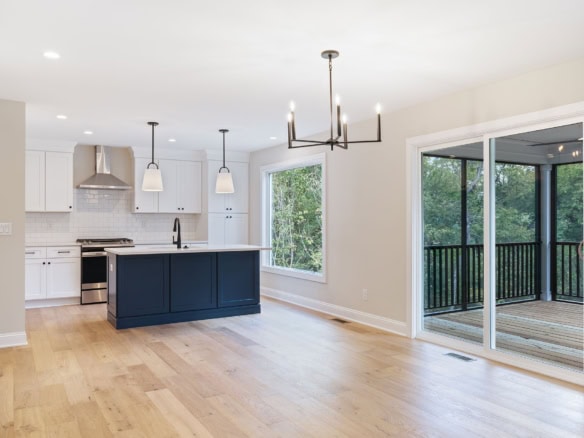 Bright, open-concept kitchen with white cabinets, navy island, and large windows.