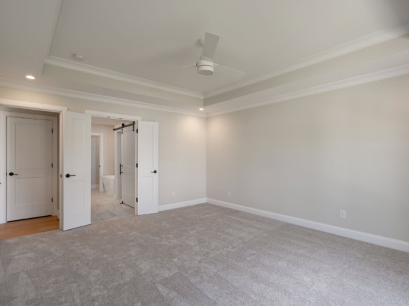 Spacious bedroom with neutral walls, plush carpet, and ceiling fan.