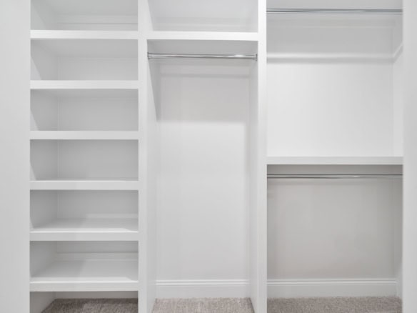 Closet interior with white shelving and hanging space.