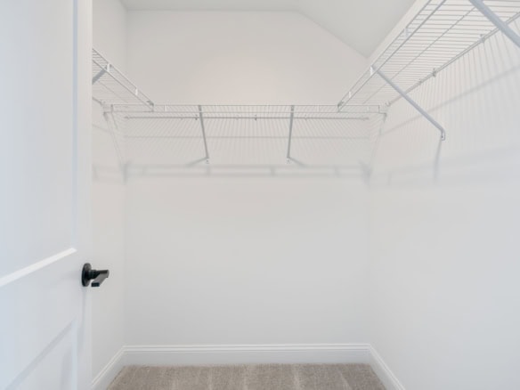 Empty walk-in closet with white wire shelving and bright lighting.