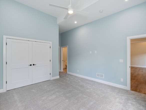 Bright, spacious bedroom with light blue walls, white closet doors, and hardwood flooring.