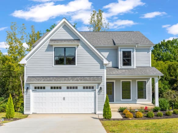New two-story house with white siding, large windows, and a two-car garage.