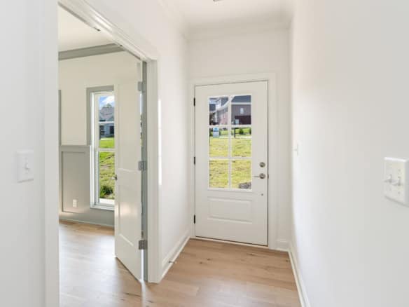 Bright, clean entryway with white walls and a glass-paneled door.