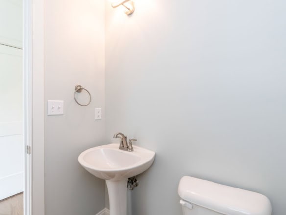 A modern bathroom with a white pedestal sink and toilet.