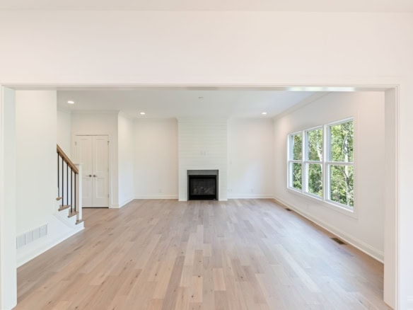 Bright living room with large windows, hardwood floors, and fireplace.