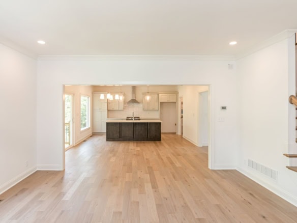 Bright open-concept kitchen and living space with hardwood floors and large windows.
