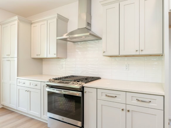 White kitchen with modern cabinetry and stainless steel stove.