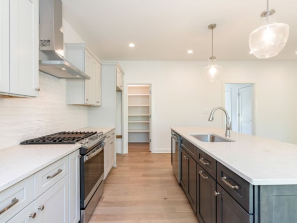 Bright, spacious kitchen with white and dark cabinetry, island, and pendant lights.