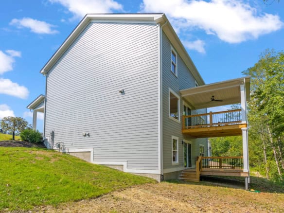 Newly built house with a spacious deck and white siding.