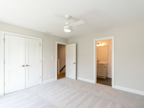 Bright, spacious bedroom with white walls, ceiling fan, and closet.