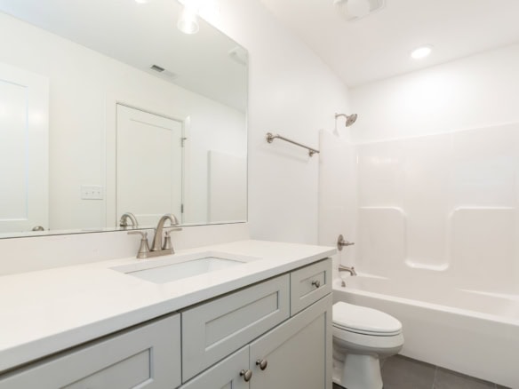 Bathroom with white vanity, bathtub, and toilet in a new home.