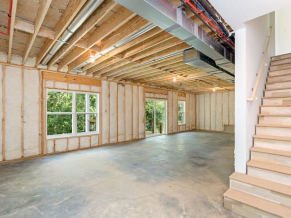 Interior view of a new construction home with exposed framing and large windows.