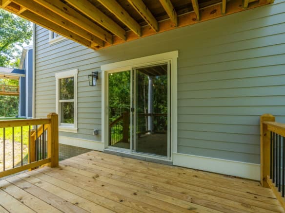 New wooden deck with sliding glass door and outdoor lighting.