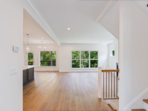 Interior view of a spacious, bright living area with large windows and hardwood flooring.