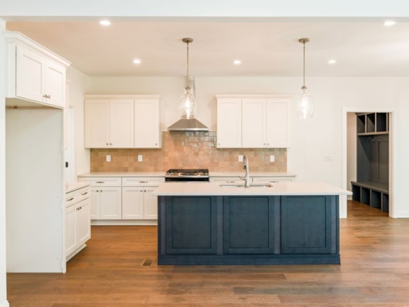 Bright modern kitchen featuring white cabinetry, a blue island, and hardwood floors.