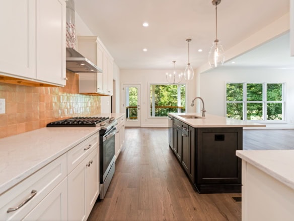 Bright modern kitchen featuring white cabinets, a central island, and large windows.