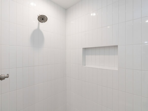 Bright white tiled shower with built-in niche.