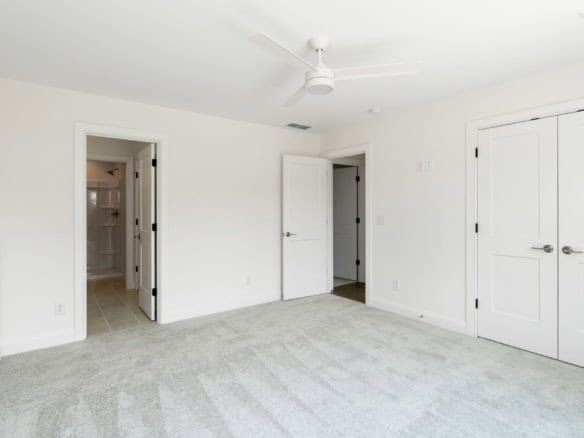 Bright, spacious bedroom with white walls and ceiling fan.