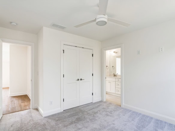 Bright, clean bedroom with white walls, closet, and attached bathroom.