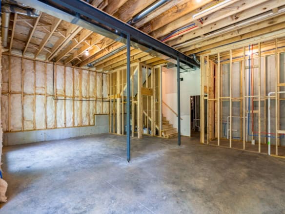 Interior view of a new home under construction with exposed framing and concrete floor.