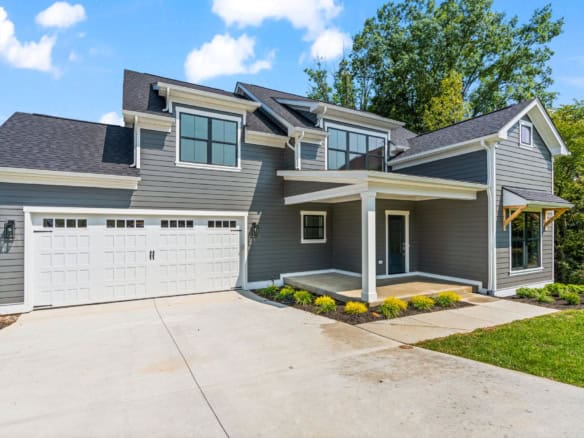 New custom-built house with gray siding, large windows, and a two-car garage.