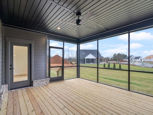 Screened porch with ceiling fan overlooking backyard and neighboring houses.