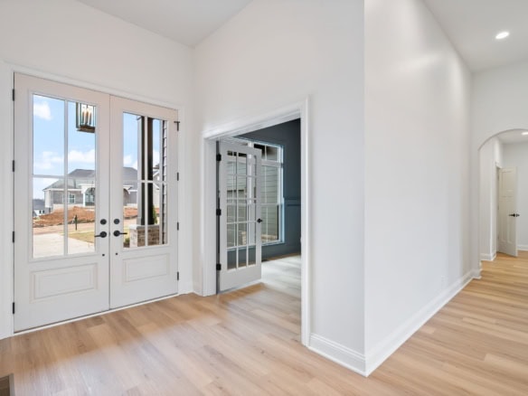 Bright entryway with double glass doors and hardwood flooring.