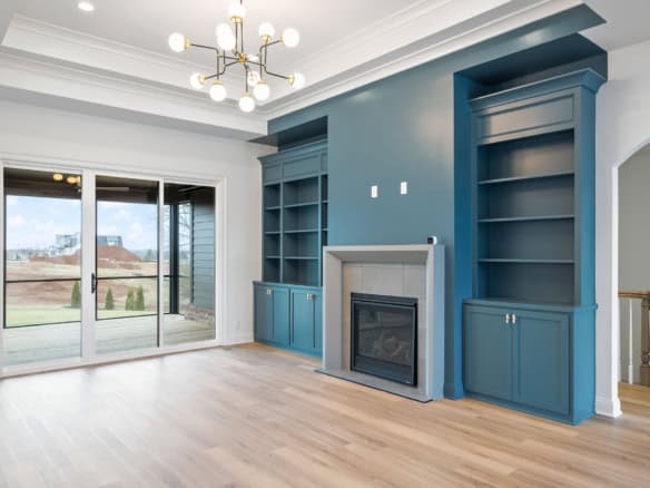 Spacious living room featuring built-in blue bookshelves, fireplace, and large sliding glass door.