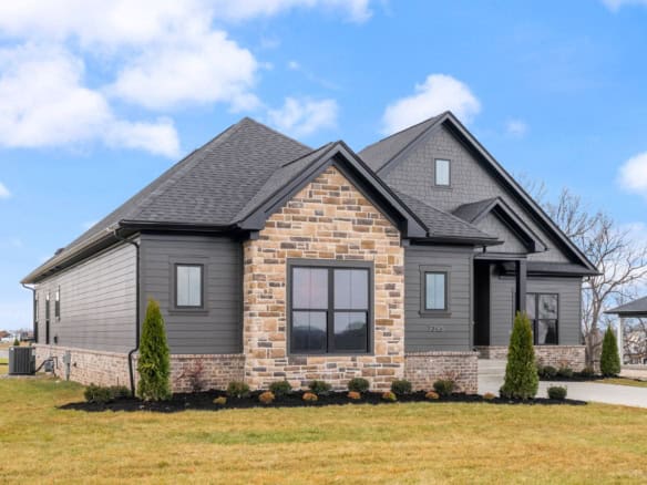 New custom-built house with dark siding, stone accents, and landscaped yard.