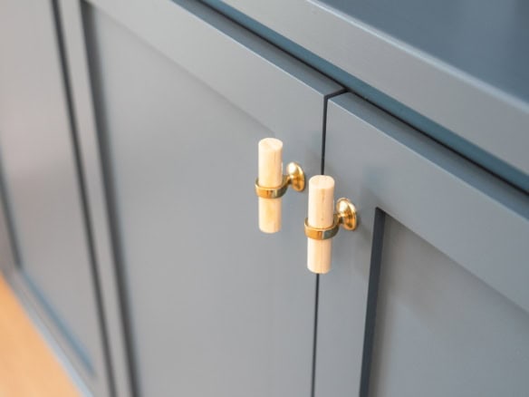 Blue kitchen cabinet with gold and white hardware handles.