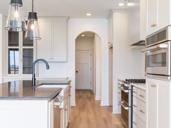 Bright, modern kitchen featuring white cabinetry and stainless steel stove.